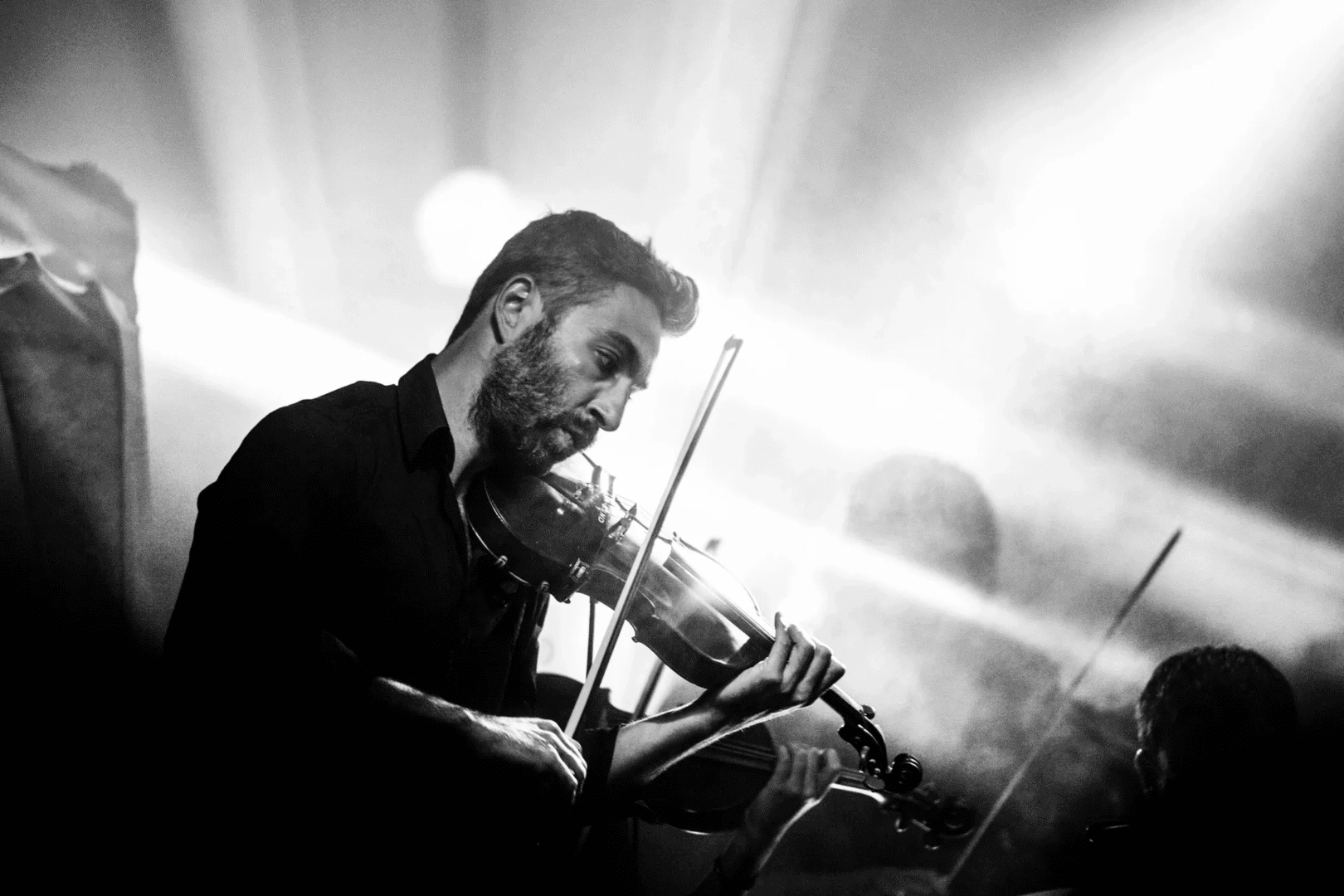 A man playing the violin in front of smoke.