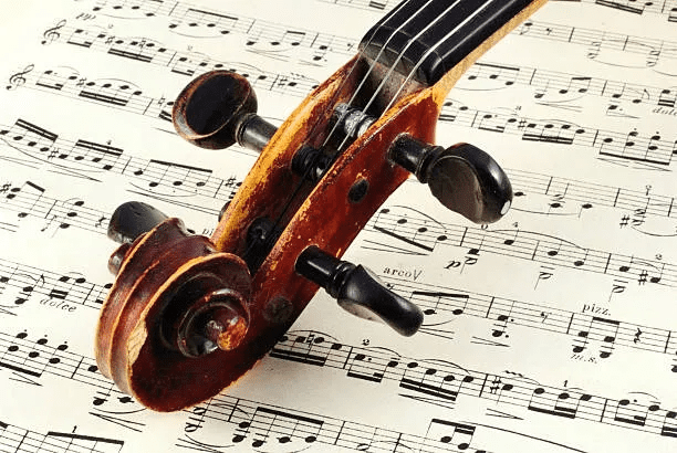 A violin sitting on top of sheet music.